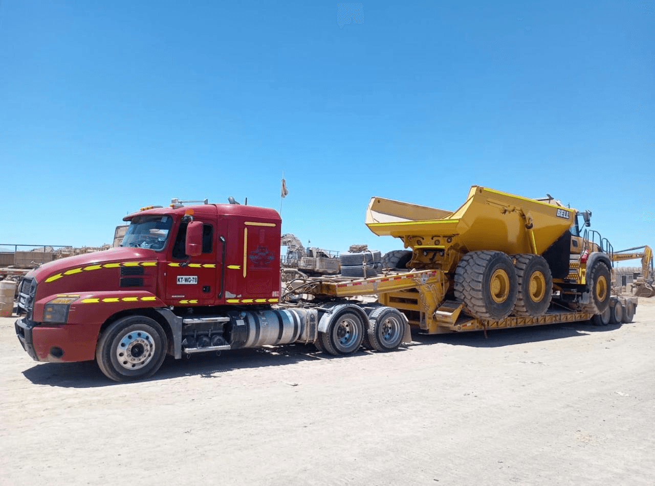Camión Mack transportando camión articulado amarillo